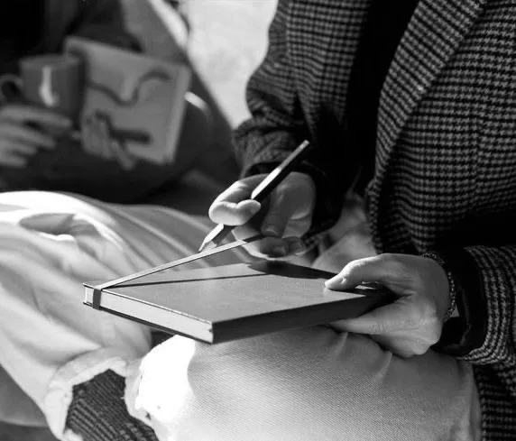 Pessoa fazendo anotação em caderno durante atividade acadêmica